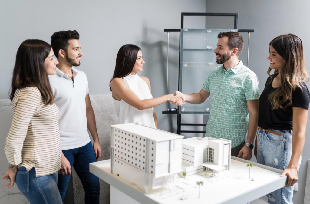 The Real Estate Team stands around a desk in an office building.