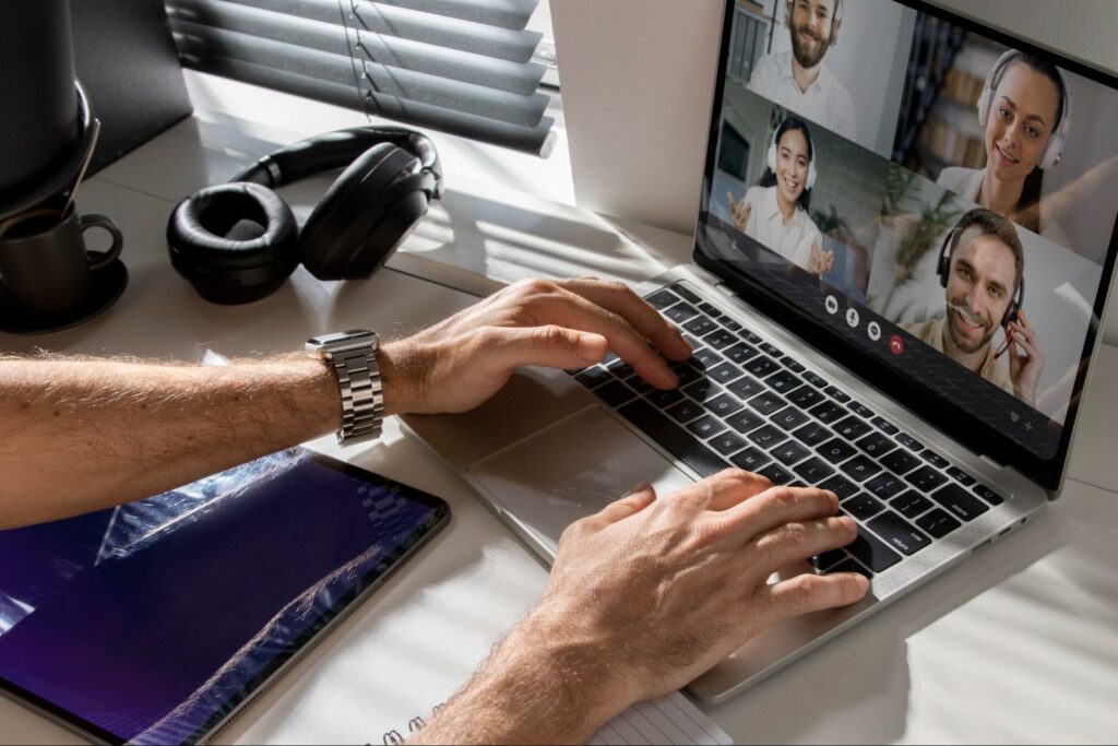 a close-up shot of male hands typing on a laptop with a virtual classroom on its screen