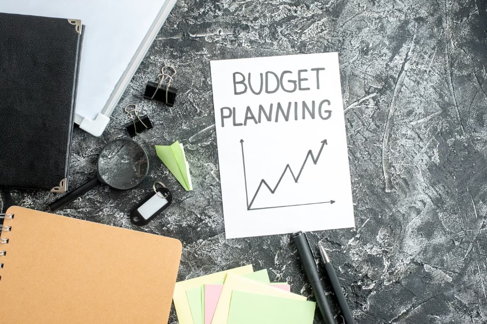 a budget-planning note with a graph and pens laying on a gray surface