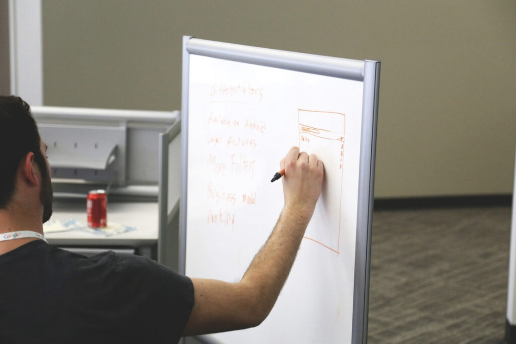 a man draws diagrams and explanations of the project on the blackboard.